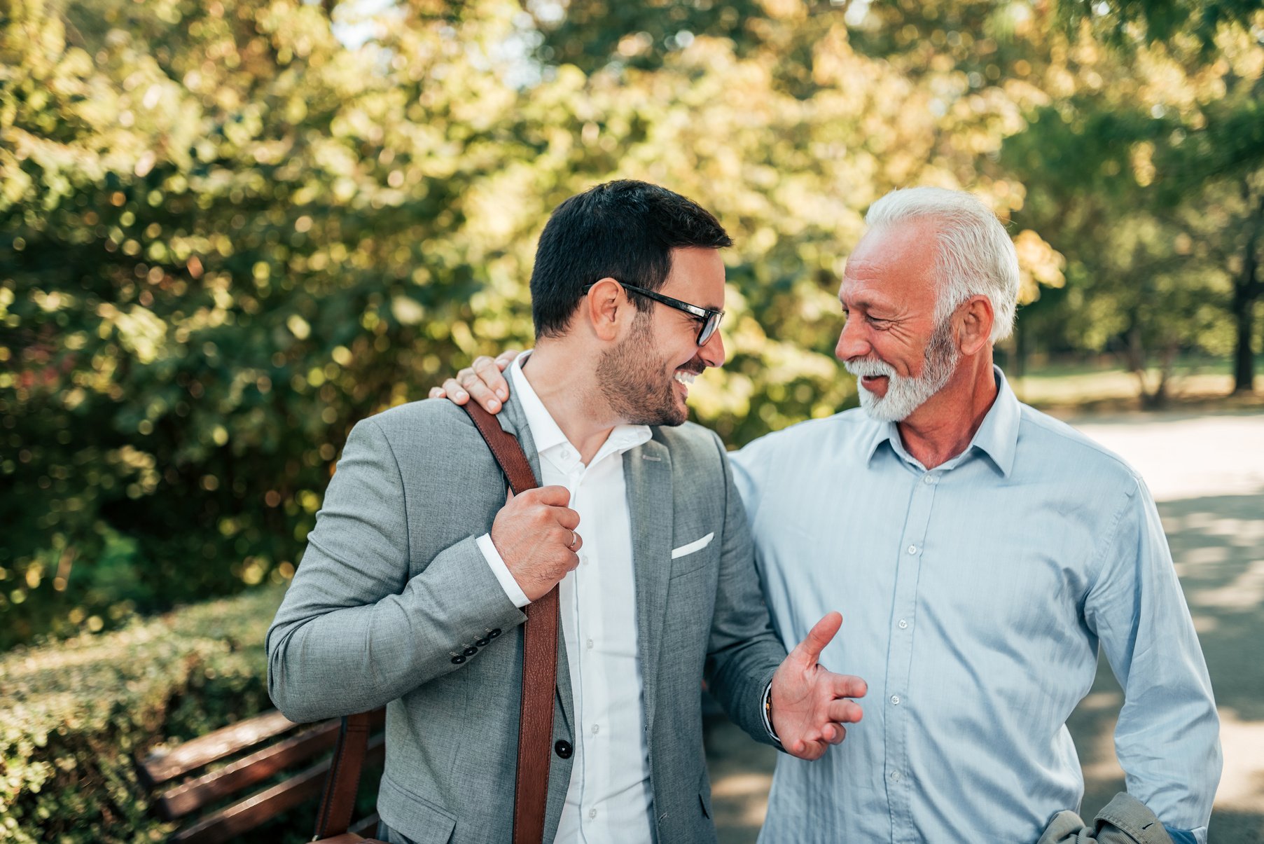 Two friendly businessman walking outdoors.