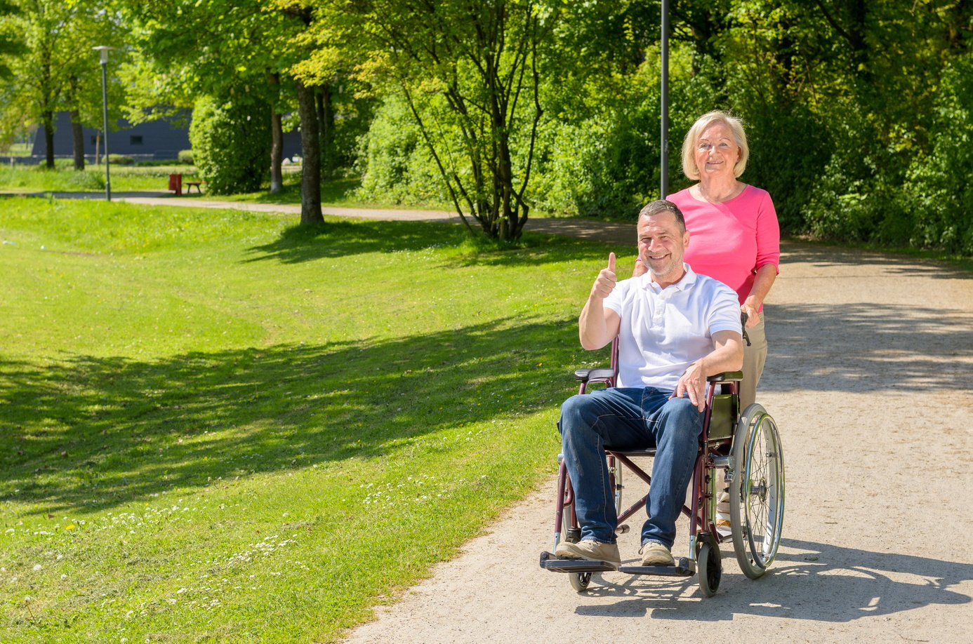 Elderly woman in pink blouse pushes wheel chair